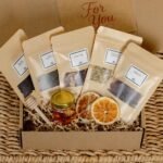 Tea and honey gift set in an open gift box with loose leaf teas, honey, dried orange, and honey dipper